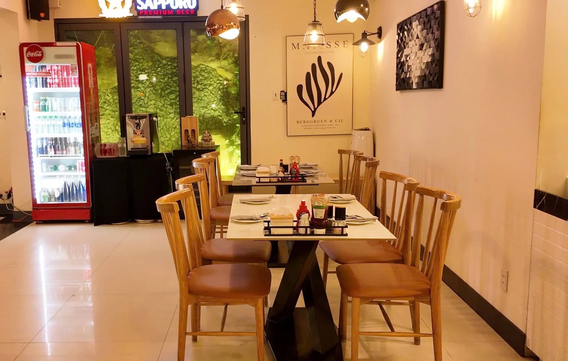Bàn ăn cạnh tranh tường và tủ lạnh đồ uống.