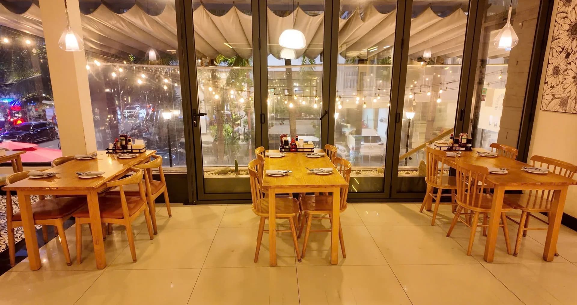 Bàn ăn bên cửa kính và dây đèn ngoài trời.